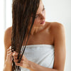 woman in towel applying leave-in silicone-free conditioner